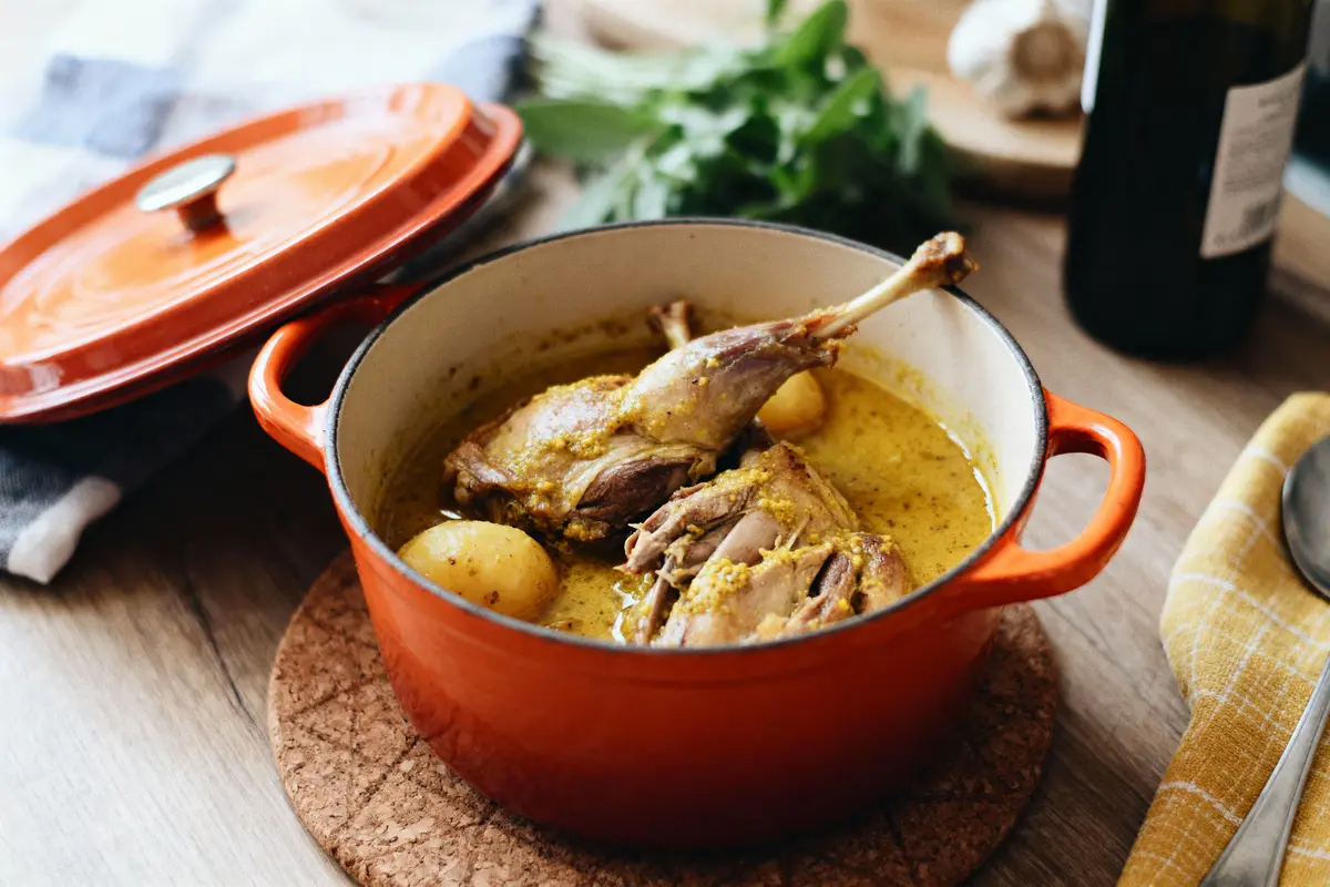 pexels-michal-pech-213601-757318 (1) Plat en cocotte rouge, contenant viande et pommes de terre dans sauce, posé sur table avec nappe à carreaux.