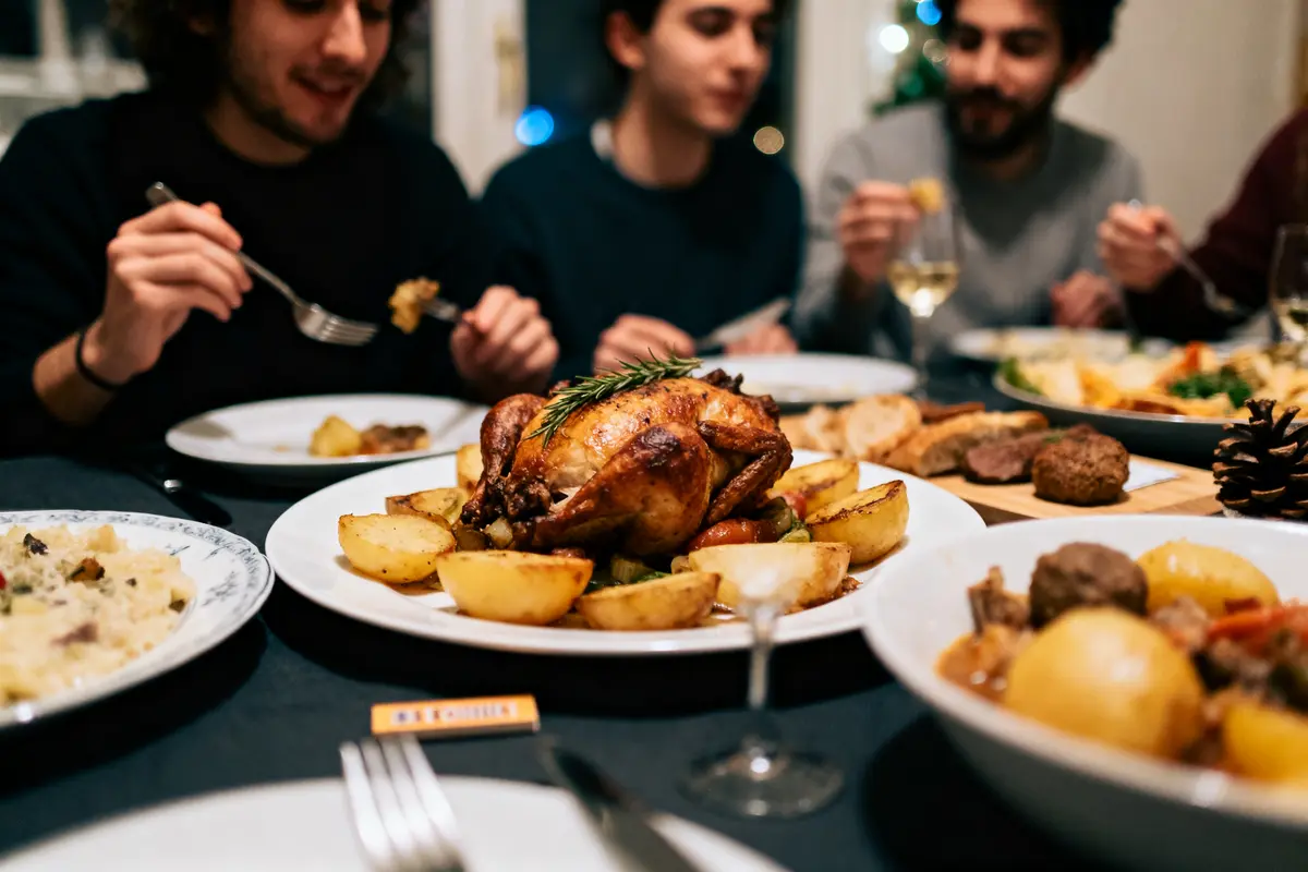 Personnes dînant autour d'un poulet rôti avec pommes de terre, partageant un repas convivial à table.