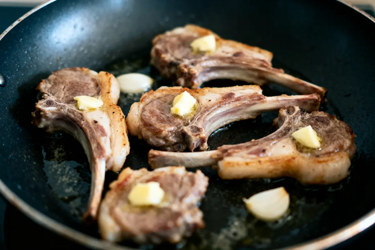 pexels-michal-pech-213601-757318 (1) Côtelettes d'agneau avec beurre et ail, poêlées dans une poêle noire.