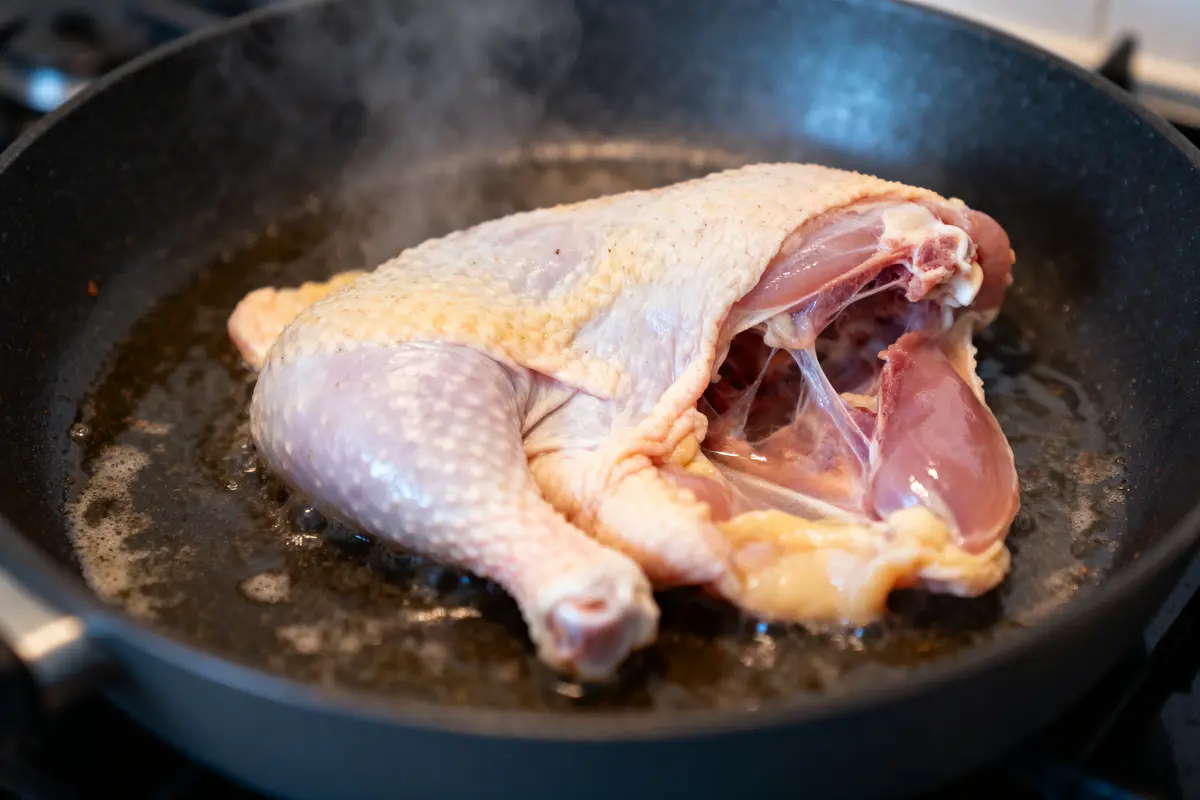 pexels-michal-pech-213601-757318 (1) Poulet entier dans une poĂȘle sur feu, en cours de cuisson, dĂ©gagement de vapeur visible.