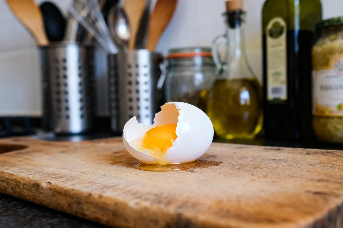 Oeuf cassé sur planche montrant le jaune combien pèse un blanc d'oeuf en cuisine