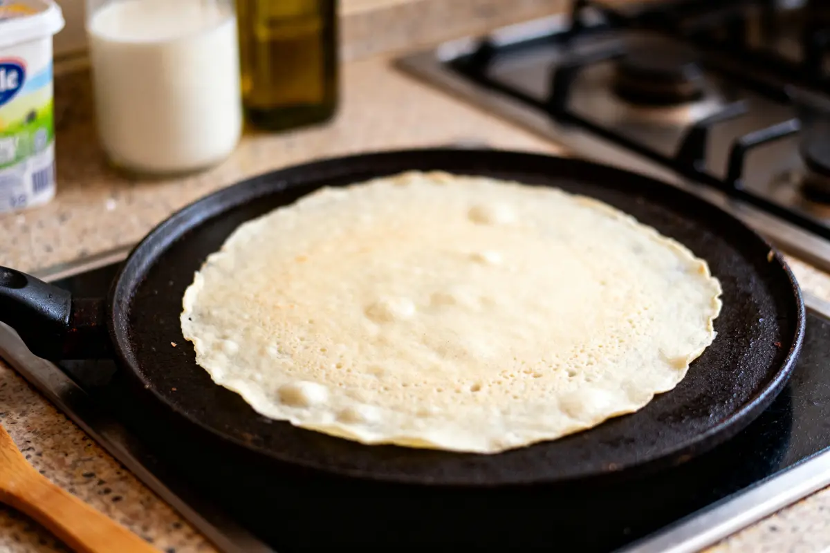 Crêpe sur une poêle chaude avec ingrédients pour recette de crêpe sans sucre en arrière-plan